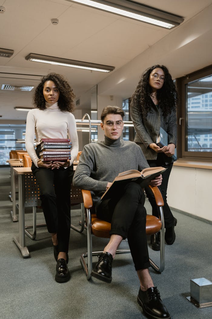 Three young adults studying amidst books in a contemporary library setting.
