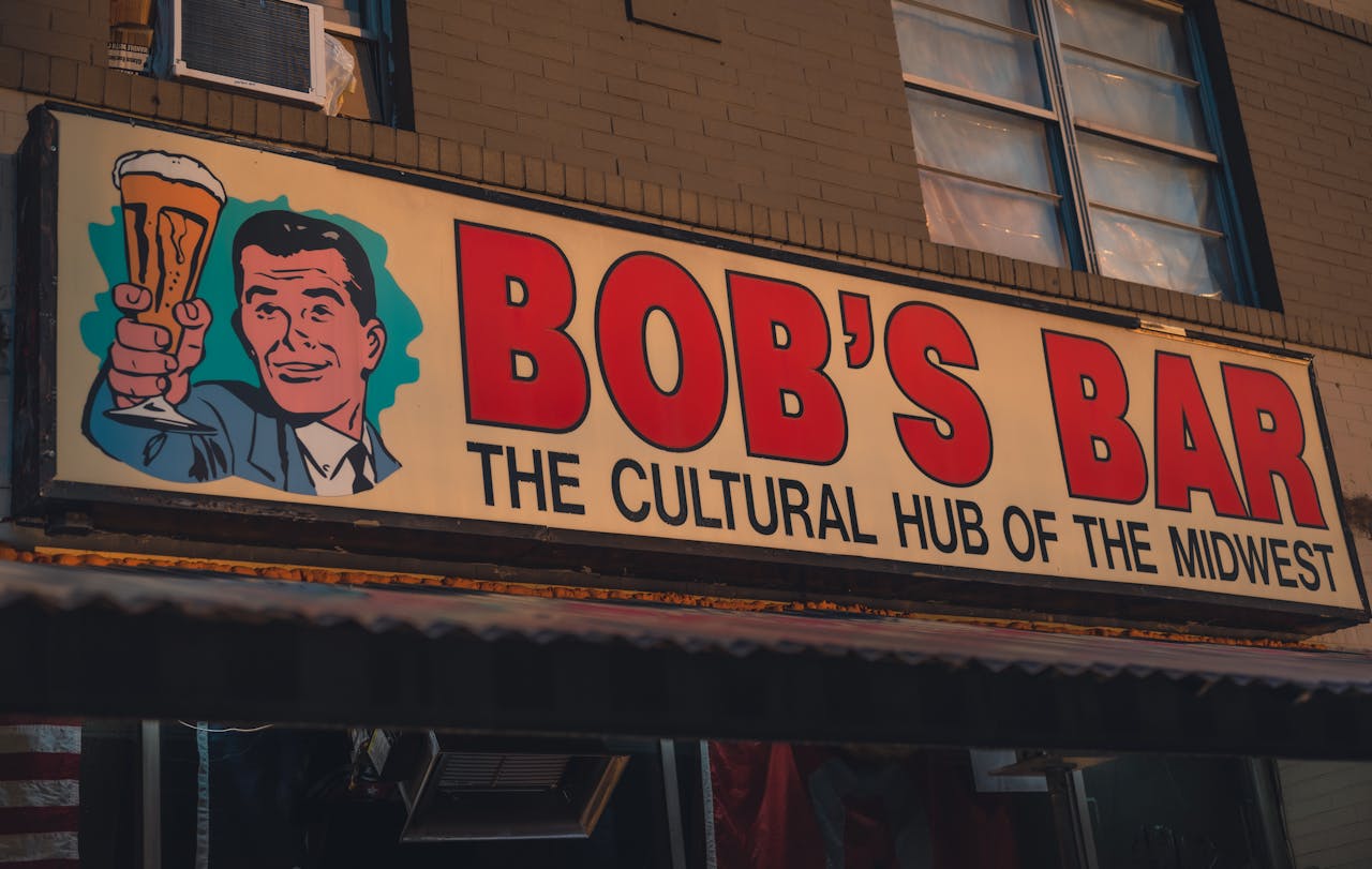 Vintage bar sign reading 'Bob's Bar: The Cultural Hub of the Midwest' with a retro illustration.